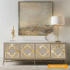 a white and gold sideboard in a living room with a painting on the wall