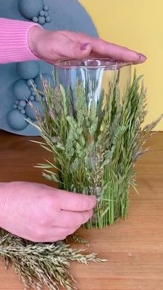 a glass vase filled with grass on top of a wooden table