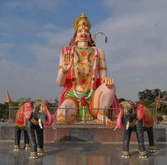 three elephants standing in front of a large statue