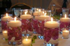 many candles are lit on a table with flowers