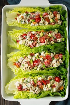 lettuce with tomatoes and chicken salad in a white dish on a wooden table