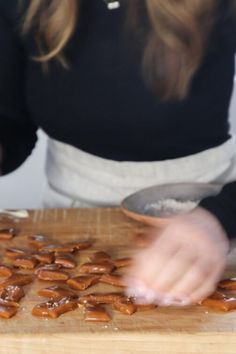 a woman in black shirt preparing food on wooden cutting board