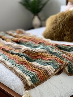 a crocheted blanket sitting on top of a bed next to a teddy bear