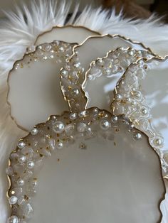 three white and gold plates with pearls on them
