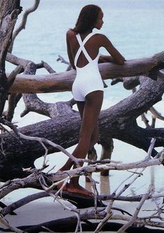 a woman in white swimsuit standing next to tree branches