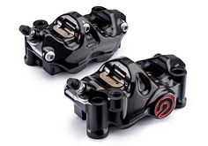 two black pedals sitting next to each other on a white surface with red and black numbers