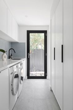 a laundry room with white cabinets and black doors, along with a washer and dryer