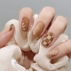 a woman's hands with brown and white nail polishes on their nails,