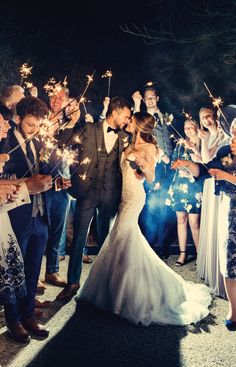 a bride and groom are surrounded by sparklers