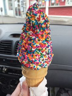 an ice cream cone filled with sprinkles on top of a car dashboard
