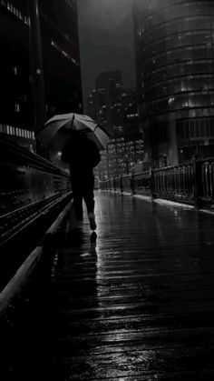 a person with an umbrella walking down the street in the rain on a rainy night