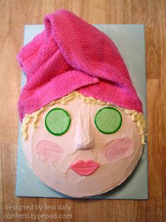 a cake shaped like a woman's face with green eyes and a pink towel on top