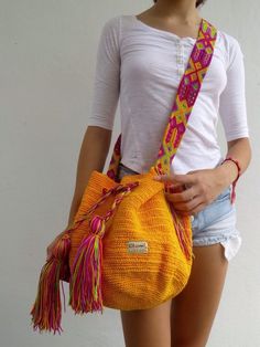 a woman holding a yellow purse with colorful tassels