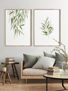 two green leaves are hanging on the wall above a couch and coffee table in a living room