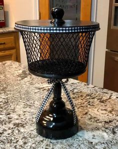 a black wire basket on top of a granite countertop in front of a door
