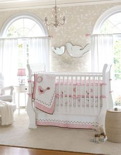 a baby's room with white furniture and chandelier
