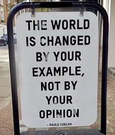 a sign that says the world is changed by your example, not by your opinion