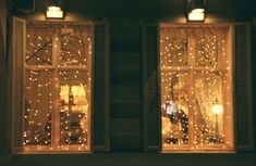 two open windows with lights on them in front of a window sill at night