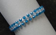a close up of a bracelet on a person's arm with blue and white beads