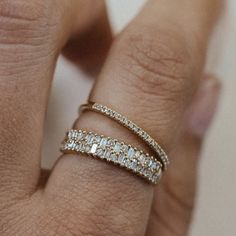 a woman's hand with a diamond ring on top of her finger and the band is