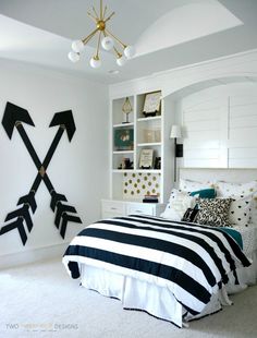 a bedroom with white walls and black and white bedding, gold accents on the headboard