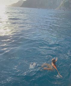 a woman swimming in the ocean with her back to the camera