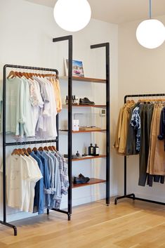 a clothing rack with clothes and shoes on it in front of two lamps hanging from the ceiling