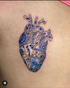 a blue and white heart shaped tattoo on the back of a woman's stomach