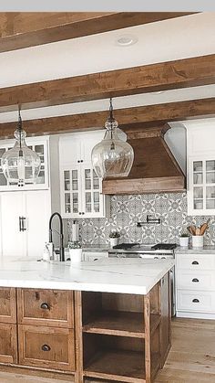a large kitchen with white cabinets and wooden flooring is pictured in this image, there are two pendant lights hanging from the ceiling