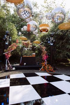 an outdoor party setup with disco balls and flowers in the center, surrounded by black and white checkered flooring