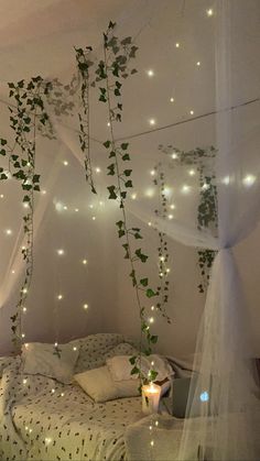 an unmade bed with white sheets and lights on the wall above it is decorated with ivy vines