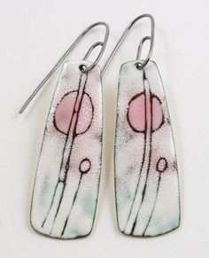 two white and pink earrings are hanging from silver earwires on a white surface