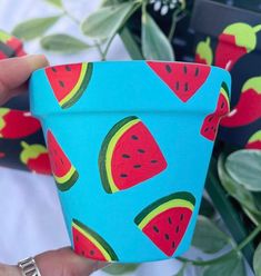 a hand holding a cup with watermelon designs on it