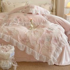 a bed with pink comforter and pillows on it in a bedroom next to a lamp