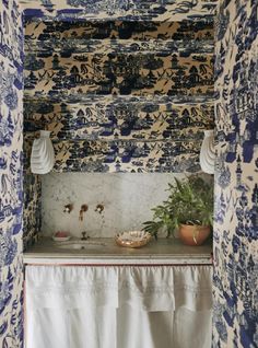a bathroom with blue and white wallpaper, sink and curtained window sill