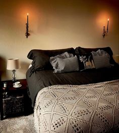 a bed with black comforter and two wall sconces