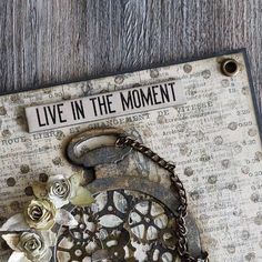 a card with an altered clock and flowers on it that says live in the moment