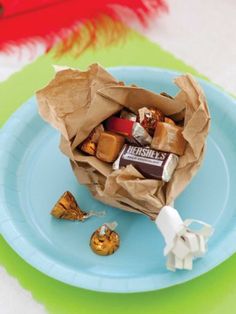 a paper bag filled with candy sitting on top of a blue plate