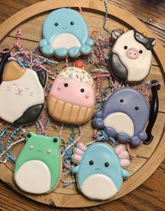 decorated cookies in the shape of animals on a wooden plate with beads and chains around them