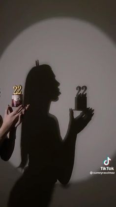 the silhouette of a woman holding a cake with candles in her hand and two other hands reaching for it