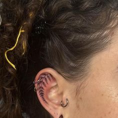 a woman's ear has a fern tattoo on the side of her left ear