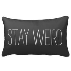 a black and white pillow with the words stay weird printed on it in white letters