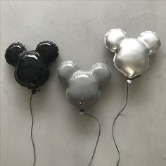 three balloons shaped like mickey mouses on a white table with black and silver decorations