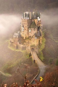an old castle on top of a hill in the fog