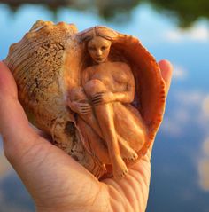 a person holding a shell with a statue in it