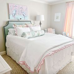 a white bed sitting in a bedroom next to a window with pink drapes on it