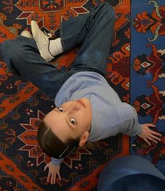 a young boy laying on the floor with his eyes wide open, looking up at the camera