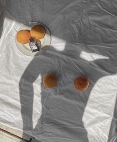 three oranges are sitting on a table with a glass and silver object in the middle