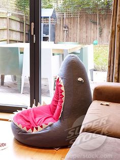 an inflatable shark chair sitting on top of a wooden table next to a sliding glass door