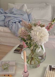 a glass vase filled with flowers on top of a coffee table next to a couch